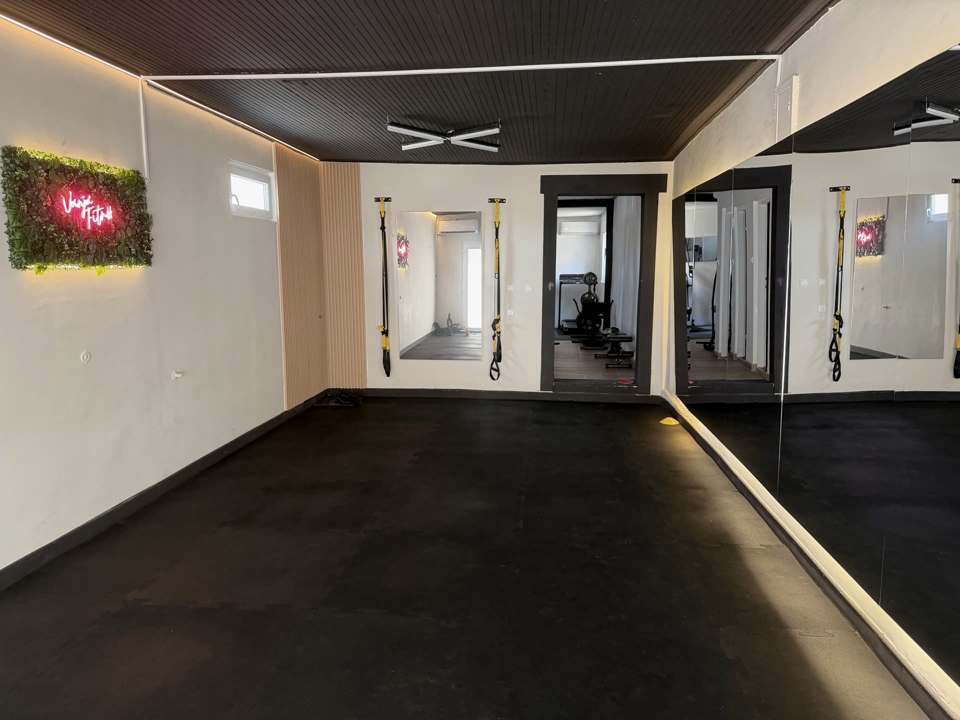 Sala za trening u fitnes studiju za žene Vanja Fitness u Sremskoj Mitrovici, sa ogledalima, TRX trakama i neonskim logom