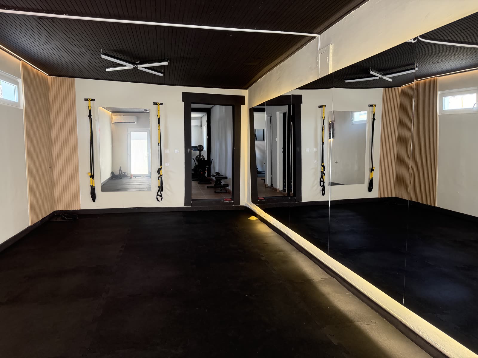 Sala za trening sa ogledalima i TRX trakama u fitnes studiju za žene u Sremskoj Mitrovici